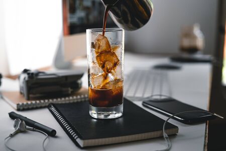 Iced coffee in a cup at the computer desk,Coffee on the desk at homeの写真素材