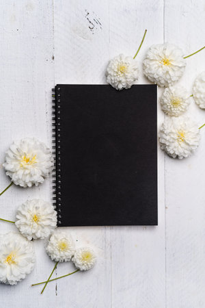 The book and white flowers on the white wooden table