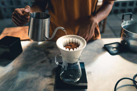 Drip coffee, barista pouring water on coffee ground with filter at homeの写真素材
