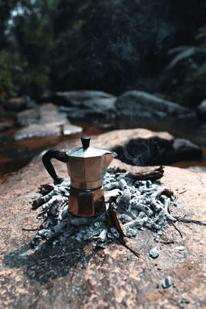Pouring coffee into a cup ,Coffee in a black cup camping in the forestの写真素材