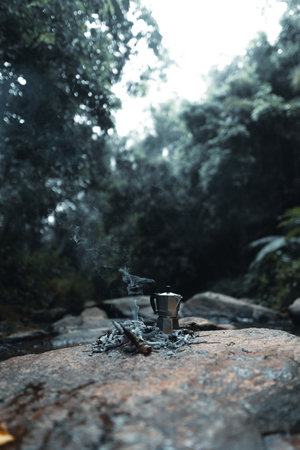 Pouring coffee into a cup ,Coffee in a black cup camping in the forestの写真素材