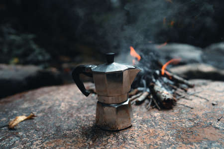 Pouring coffee into a cup ,Coffee in a black cup camping in the forestの写真素材