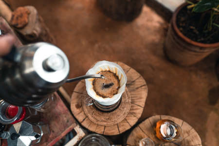 Man adding hot water into coffee dripper above glass jar.の写真素材