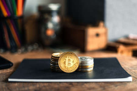 Golden bitcoins placed on a wooden desk in the house.の写真素材