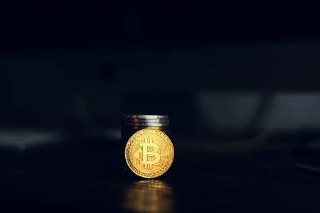 Golden bitcoins placed on a wooden desk in the house.の写真素材