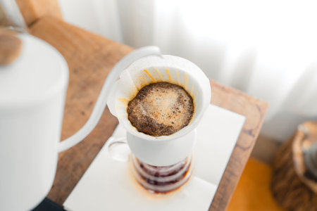 Pouring a hot water over a drip coffee on the table in the room