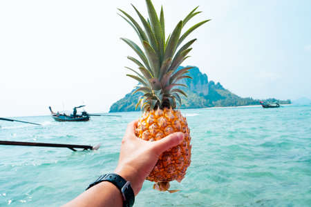Pineapple in hand on a boat at sea,Fresh fruit eaten on a boat while traveling at sea.の写真素材