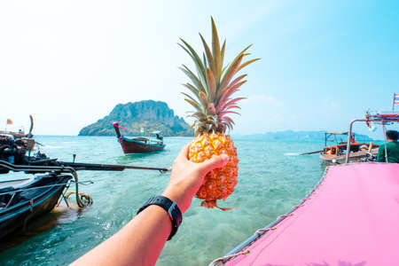 Pineapple in hand on a boat at sea,Fresh fruit eaten on a boat while traveling at sea.の写真素材