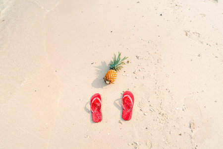 pineapples and red flip flops on the beach.