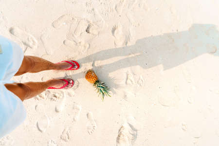 pineapples and red flip flops on the beach.の写真素材