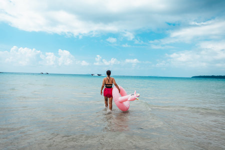 A woman walks into the clear sea on Koh Phrao. Rubber rings for playing in the water in summer