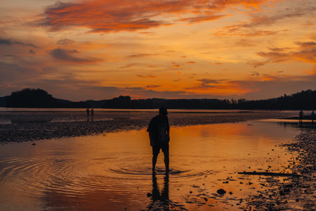 Silhouette of woman on calm beach and sky In the evening at Ao Nang, Krabi, go to the beach.の写真素材