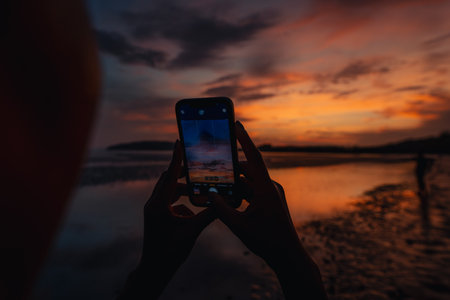 Smartphone takes photos of the calm beach and sky at In the evening at Ao Nang, Krabi, go to the beach.の写真素材