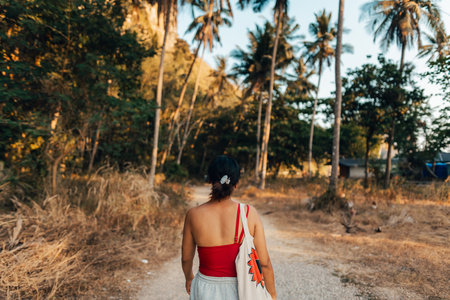 Woman with coconut trees, walkway to the beach in the eveningの写真素材