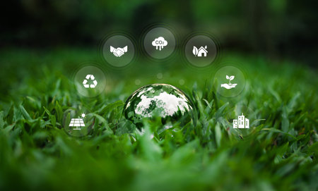 Environment and nature conservation glass ball on grass showing the world and surrounding environment icons,In natural green tonesの写真素材