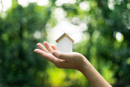 Eco-friendly house concept, wooden house decoration on hand green natural backgroundの写真素材