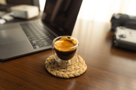 Espresso shot in glass on wooden desk in the morning at homeの写真素材