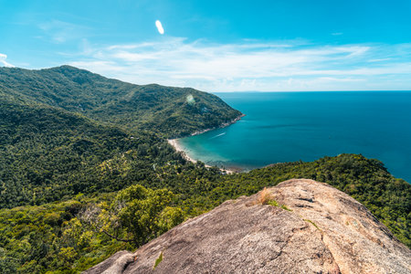 An exquisite aerial view of Bottle Beach, embraced by lush green forests, with vibrant turquoise waters contrasting against the azure sky on a summer day in Koh Phangan, Thailand.の写真素材
