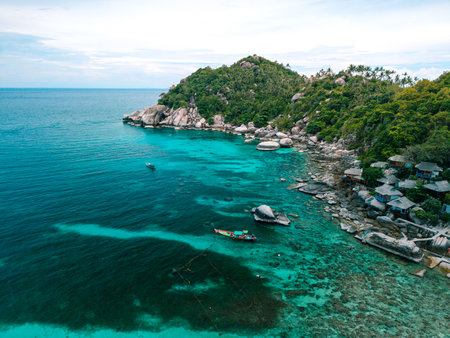 erial view captures the essence of a tropical paradise. A traditional colorful Thai longtail boat with a person standing on it floats gracefully on the crystal-clear turquoise waters.の写真素材