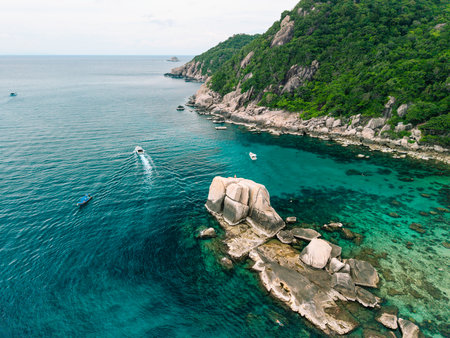 erial view captures the essence of a tropical paradise. A traditional colorful Thai longtail boat with a person standing on it floats gracefully on the crystal-clear turquoise waters.の写真素材
