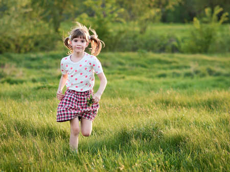 Girl running through the green grassの写真素材