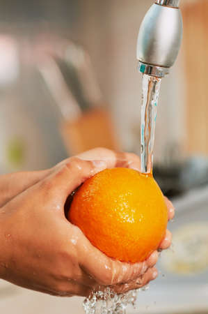 The orange is being washed in the stream of waterの写真素材