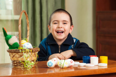 funny boy colored Easter eggs sitting at the table