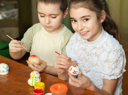 brother and sister painted Easter eggs at the tableの写真素材