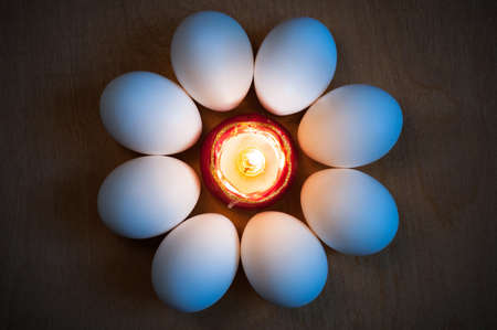 Easter eggs are laid around the candle in the form of a flowerの写真素材