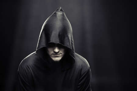 a guy in a black robe standing in the dark under the rays of the moonの写真素材