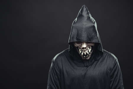 skeleton in a black robe standing in the darkの写真素材