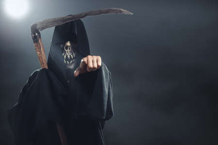 death with scythe standing in the fog at night and points to youの写真素材