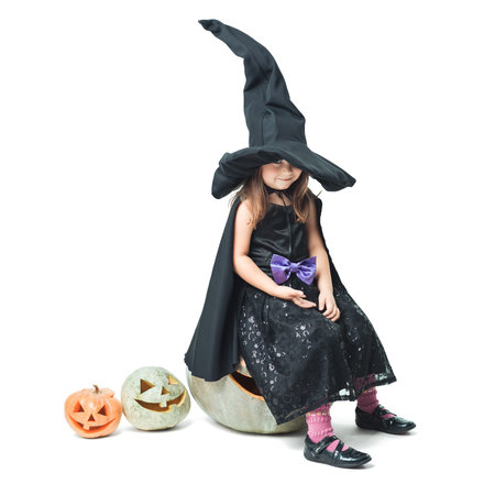 little witch sits on a halloween pumpkin