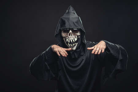 jolly skeleton  in a black robe with glasses dancing in the dark under the rays of the moonの写真素材