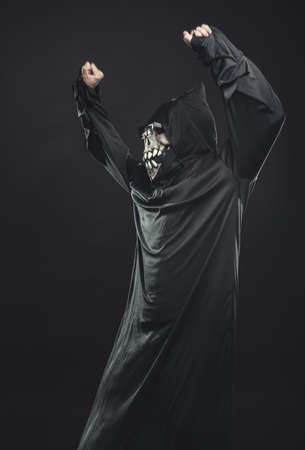 jolly skeleton  in a black robe with glasses dancing in the dark under the rays of the moonの写真素材