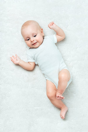 Pretty baby  is lying on the white carpet