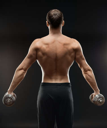 bodybuilder does exercise with dumbbells to shoulder backの写真素材