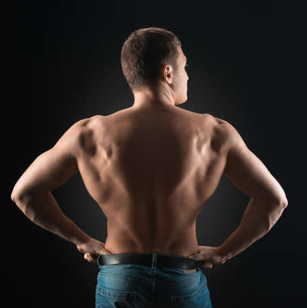 bodybuilder showing muscles back in the darkの写真素材