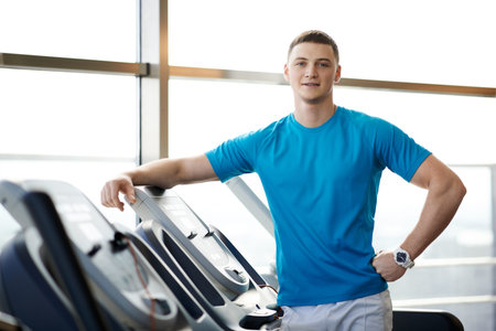Coach standing in the gym near simulators
