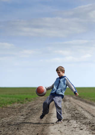 boy playing with a ball on the mud roadの写真素材