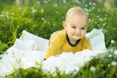 little child lying on a diaper the grass and smilingの写真素材