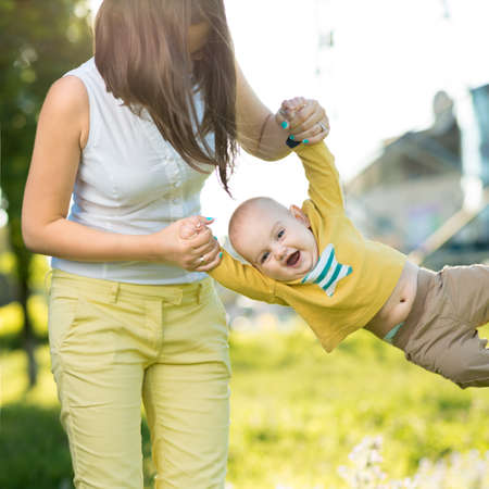 Mom throws baby in her arms up in the parkの写真素材