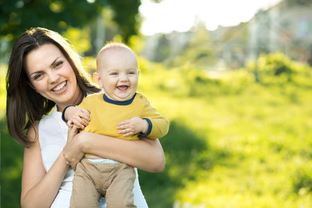 Happy mother holding a young son in the park