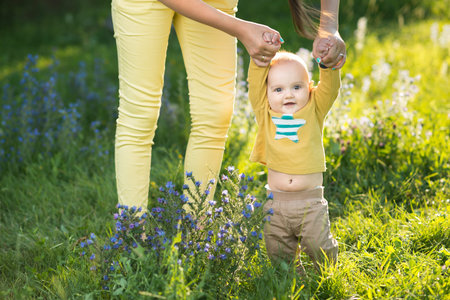 Mom teaches son walking grass on the lawn