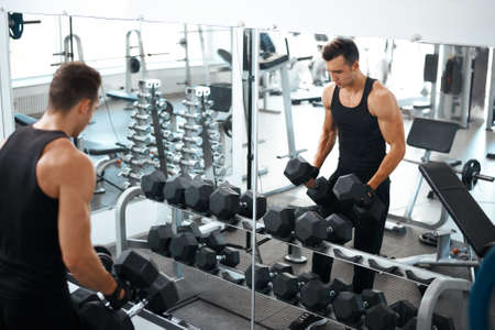 man doing exercises dumbbell bicep muscles in the gymの写真素材
