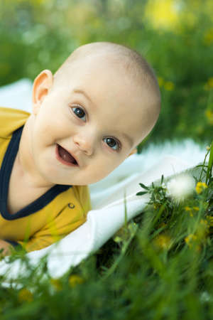 little child lying on a diaper the grass and smilingの写真素材