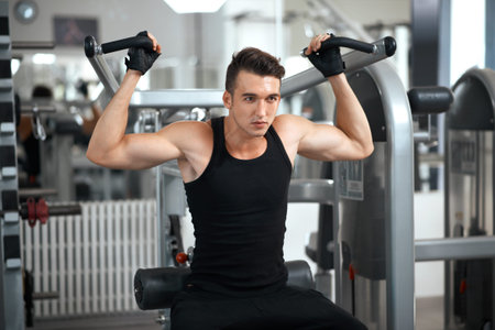 man exercising in trainer for dorsi muscles in the gym