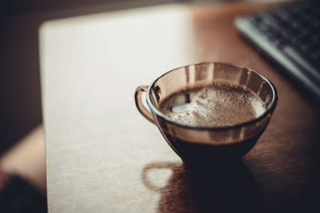 cup of coffee on  table near  keyboard in  morningの写真素材
