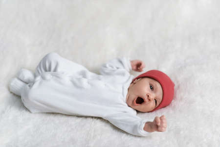 newborn stretches lying on white furの写真素材