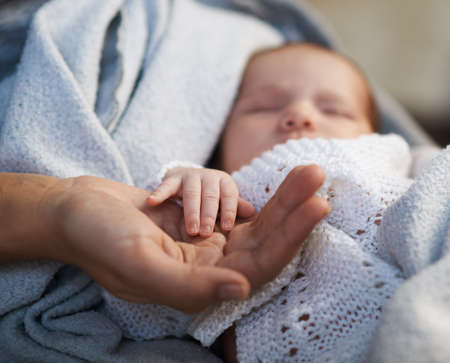 Mom keeps a miniature hand newborn baby in handsの写真素材